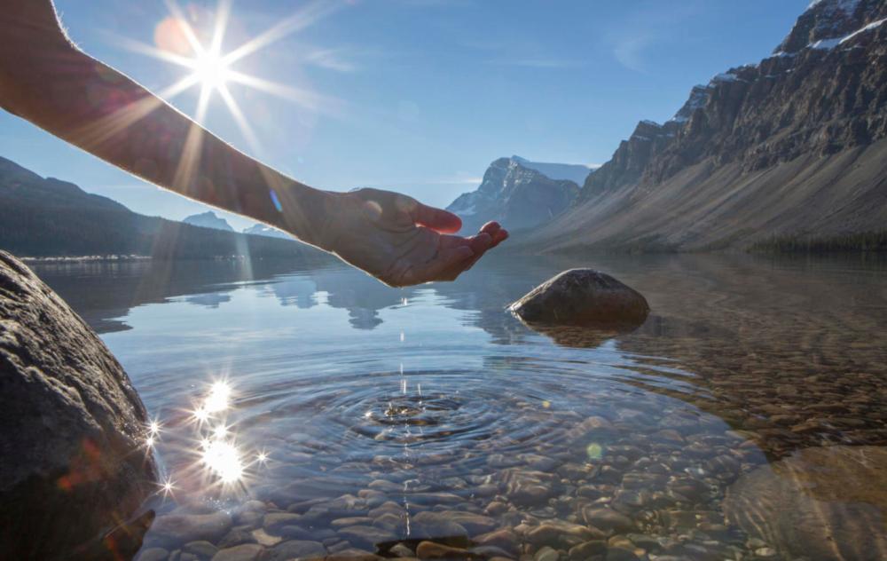 Human hand cupped to catch fresh water from mountain lake